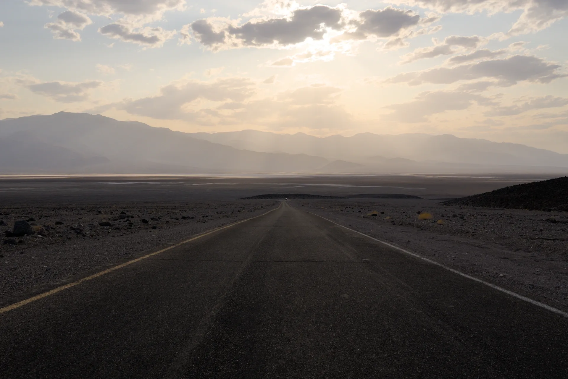 Straight road with sunbeams through the valley.