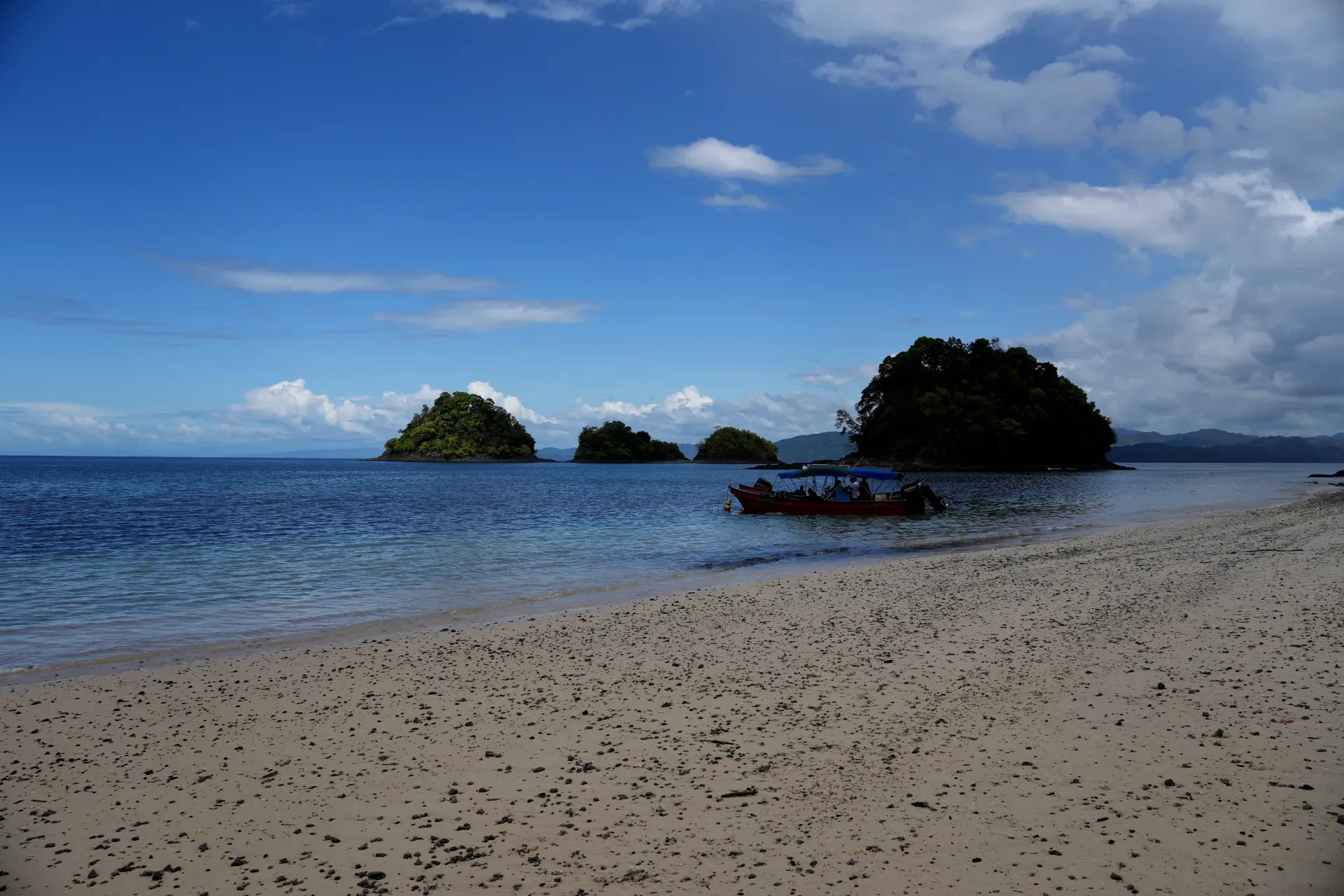 A beach with islands and a small boat.