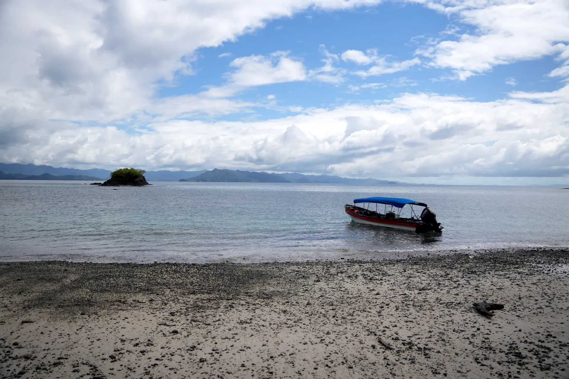 A boat near a rocky island beach.