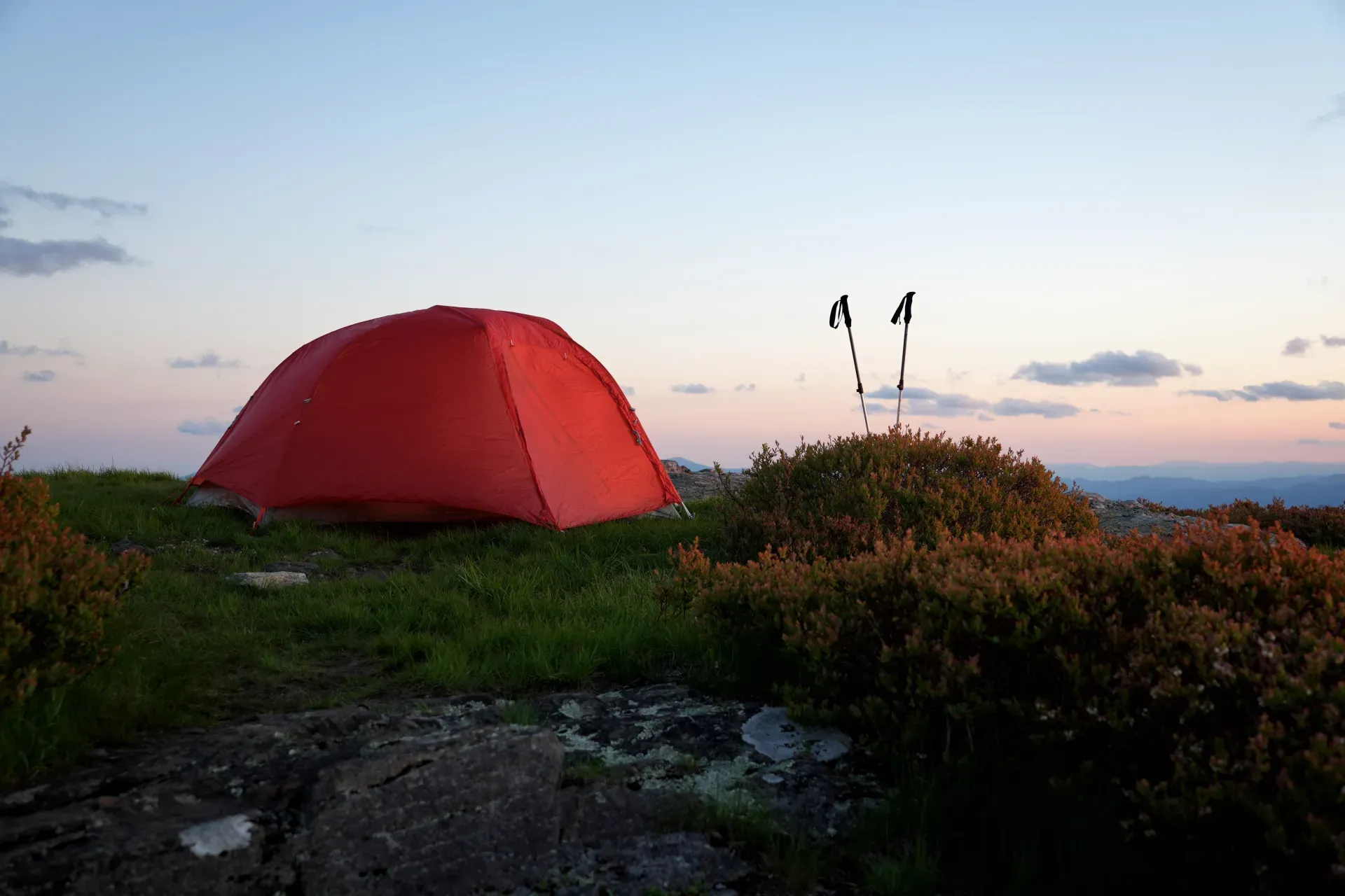 A red tent with trekking poles.