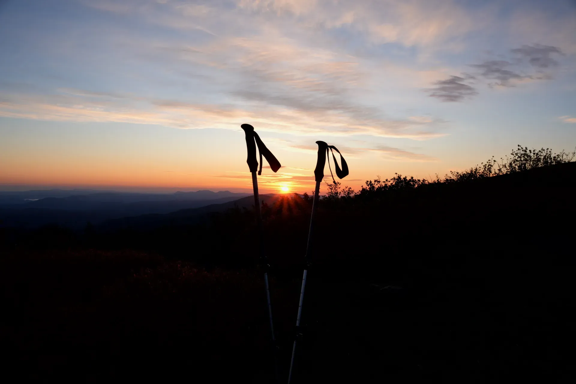 Trekking poles silhouetted at sunrise.